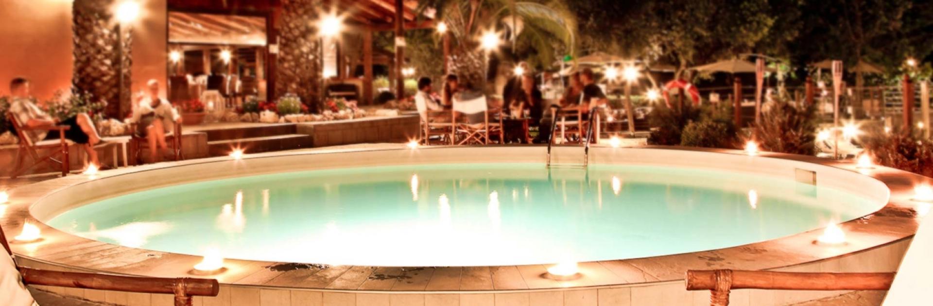 A cozy night poolside with palm trees and ambient lighting.