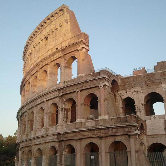 The Colosseum in Rome, an ancient amphitheater, illuminated by the evening sun.