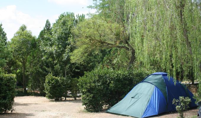 Une tente bleue installée dans un camping verdoyant.