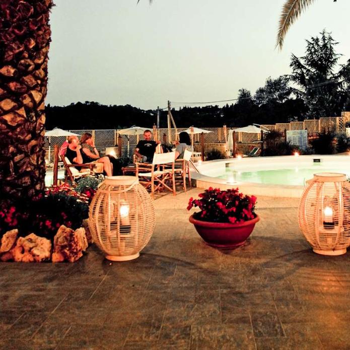 Evening by the pool with lanterns and people relaxing.
