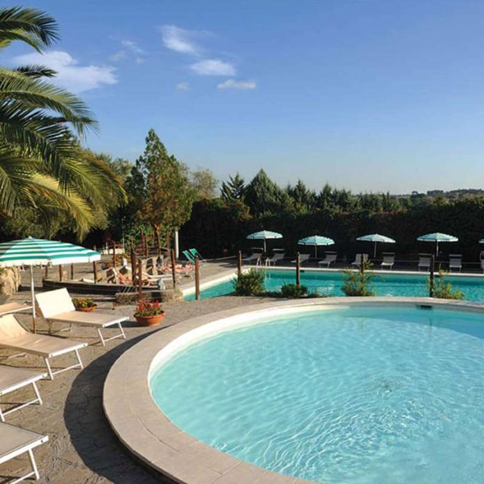Ein ruhiger Poolbereich mit Liegestühlen und Sonnenschirmen unter klarem, blauem Himmel.