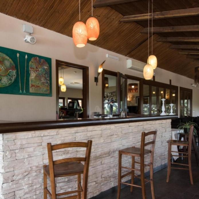 Bar convivial avec plafond en bois, comptoir en pierre et décoration artistique.
